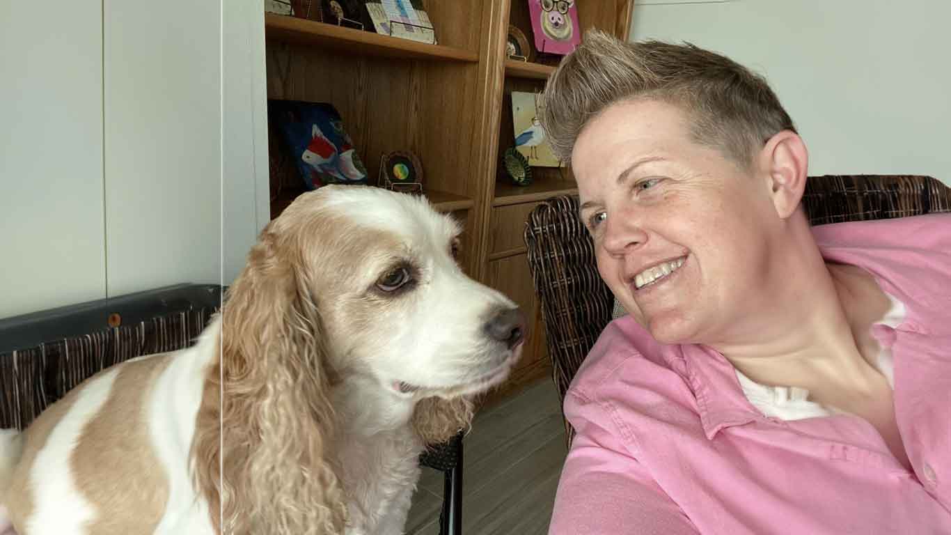 Person smiling looking at a cocker spaniel dog.
